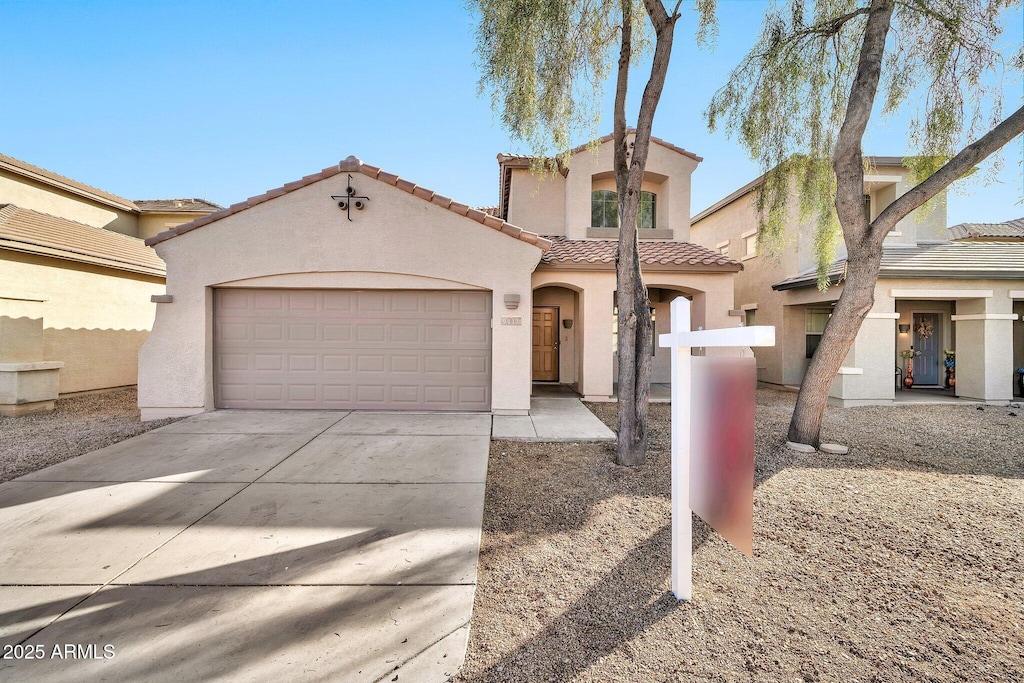 mediterranean / spanish home featuring driveway, an attached garage, a tiled roof, and stucco siding