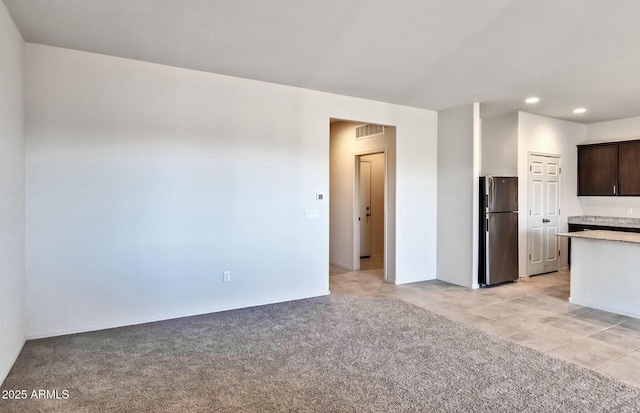 kitchen featuring dark brown cabinets, light carpet, and stainless steel refrigerator