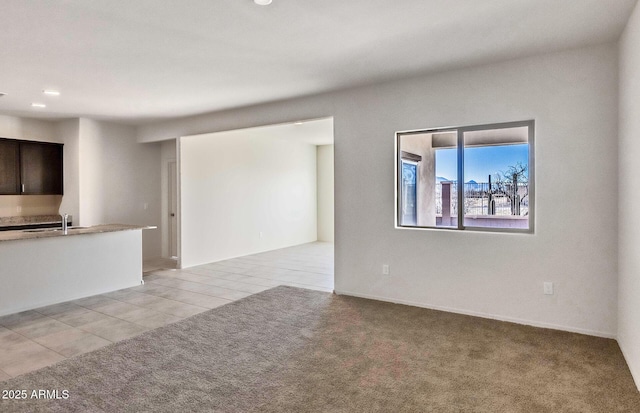 unfurnished living room featuring sink and light carpet