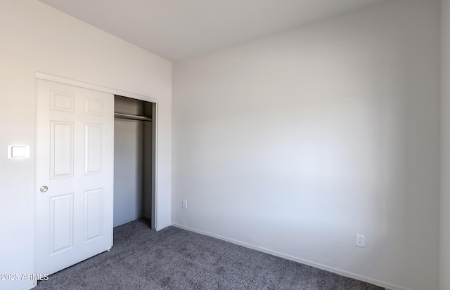 unfurnished bedroom featuring dark colored carpet and a closet