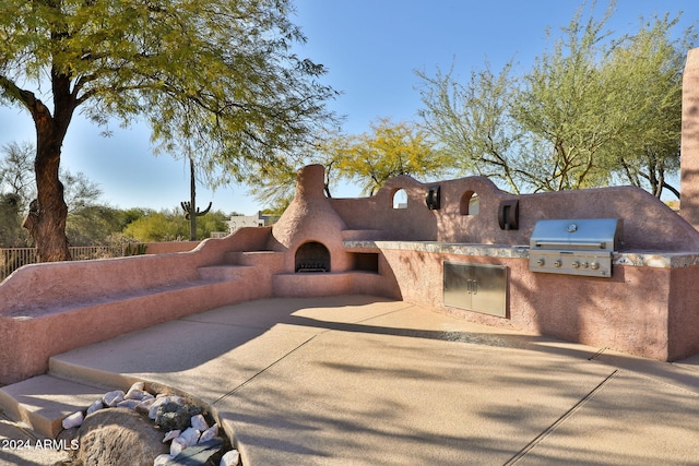 view of front of home featuring area for grilling, a patio area, and exterior fireplace