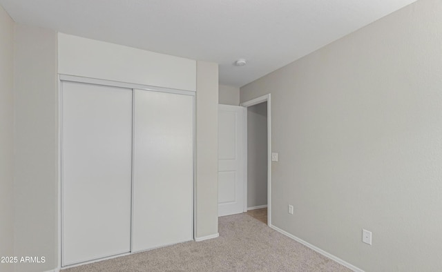 unfurnished bedroom featuring light colored carpet and a closet