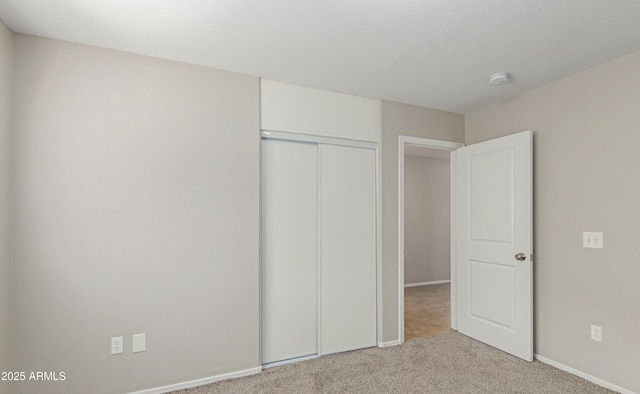 unfurnished bedroom featuring light carpet and a closet