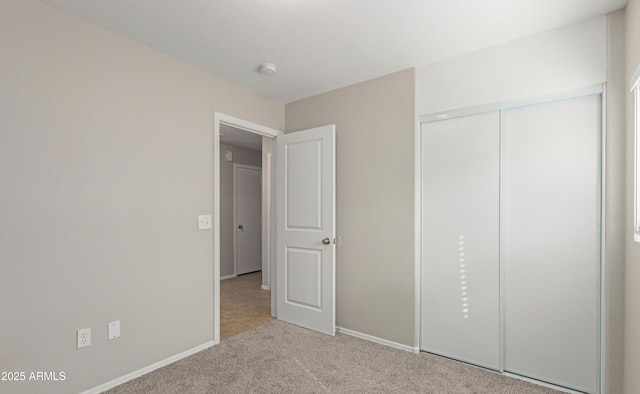 unfurnished bedroom with light colored carpet and a closet