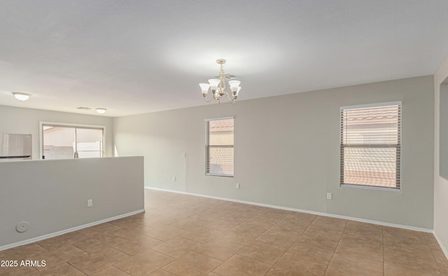 tiled spare room featuring a notable chandelier