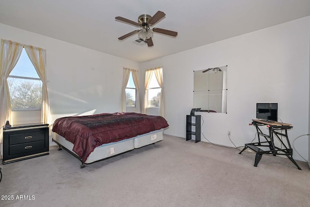 bedroom featuring ceiling fan, light carpet, and multiple windows