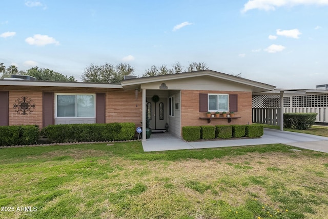 view of front of home featuring brick siding, driveway, and a front yard