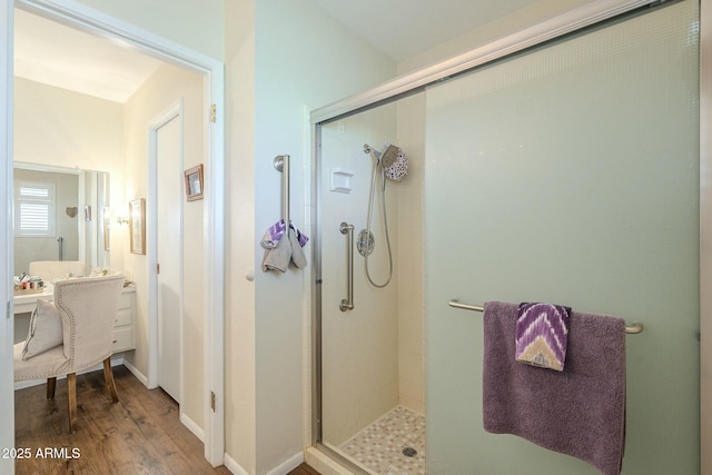 bathroom with baseboards, wood finished floors, and a shower stall