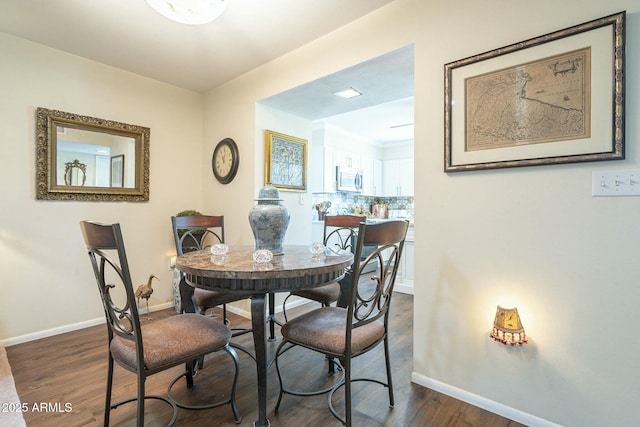 dining space featuring dark wood finished floors and baseboards