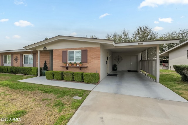 view of front of house featuring brick siding, an attached carport, driveway, and a front yard