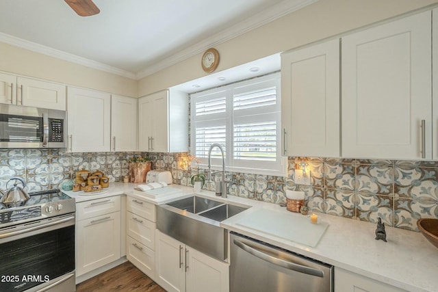 kitchen featuring stainless steel appliances, crown molding, light countertops, and a sink