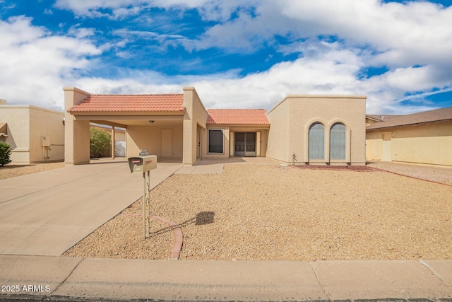 view of front of property with a carport, stucco siding, driveway, and a tile roof