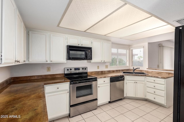 kitchen with dark countertops, visible vents, white cabinets, black appliances, and a sink