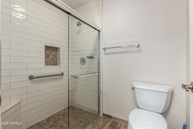 full bathroom featuring baseboards, wood finished floors, toilet, and a stall shower