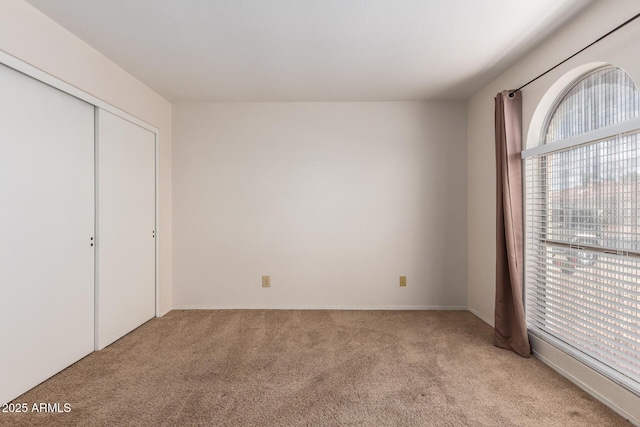 unfurnished bedroom featuring light carpet and a closet