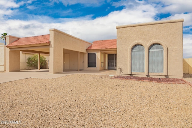 back of house featuring stucco siding, a patio, and a tiled roof