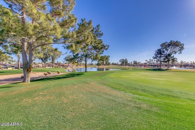 view of property's community with view of golf course, a lawn, and a water view