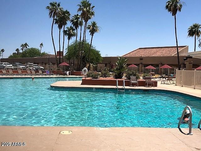 community pool with a patio and fence