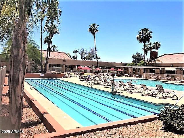 community pool with a patio area and fence