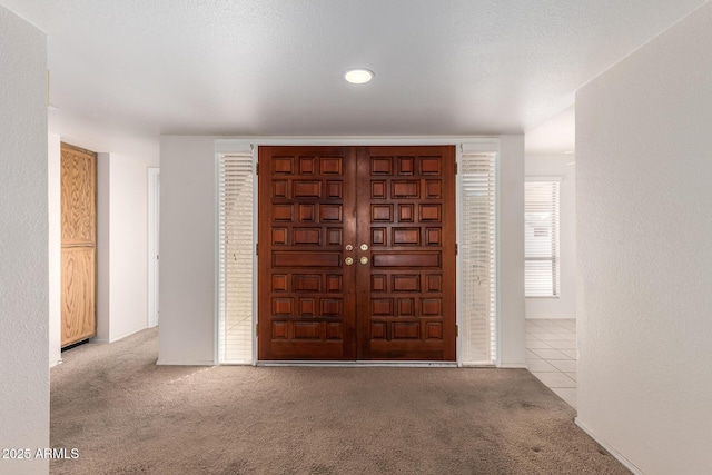 entryway with tile patterned floors and carpet