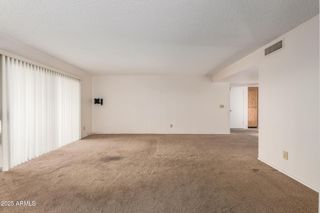 carpeted spare room with visible vents and a textured ceiling