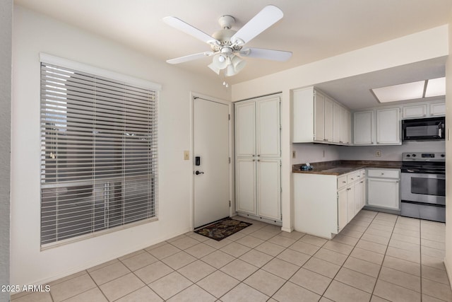 kitchen with light tile patterned floors, a ceiling fan, stainless steel electric stove, black microwave, and dark countertops