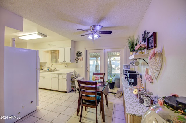 kitchen with white cabinets, ceiling fan, light tile patterned floors, a textured ceiling, and white fridge