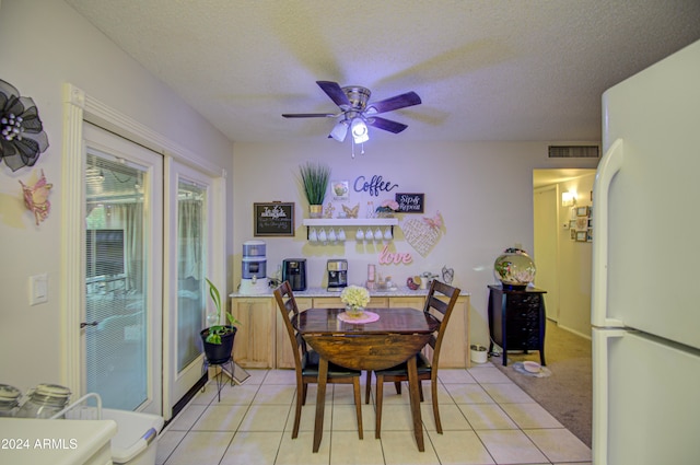 tiled dining space with a textured ceiling and ceiling fan