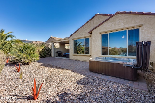 back of property featuring a patio area and a hot tub