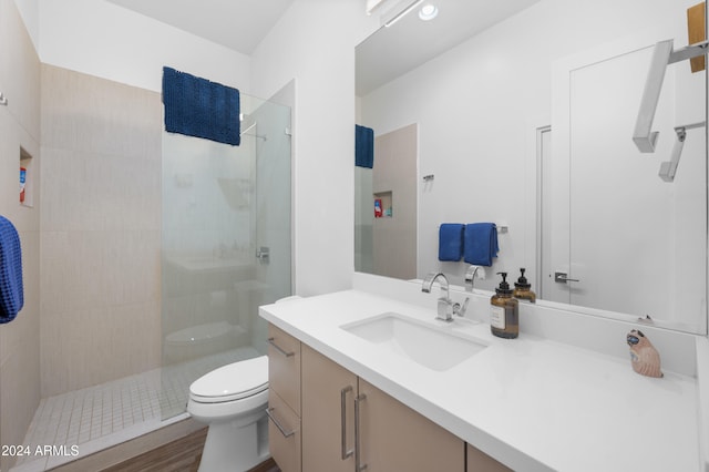 bathroom featuring tiled shower, vanity, and toilet