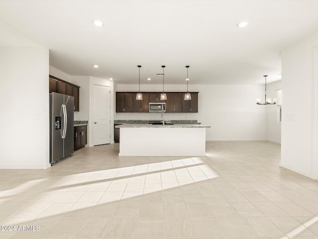 kitchen with pendant lighting, a kitchen island with sink, an inviting chandelier, stainless steel appliances, and light stone countertops