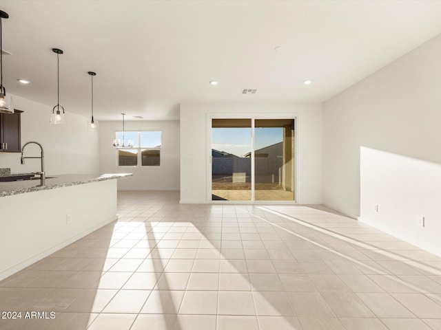 unfurnished living room with light tile patterned flooring, sink, and a notable chandelier