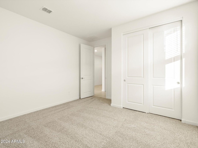 unfurnished bedroom with light colored carpet and a closet