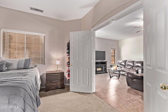 bedroom featuring visible vents, a glass covered fireplace, and light tile patterned floors