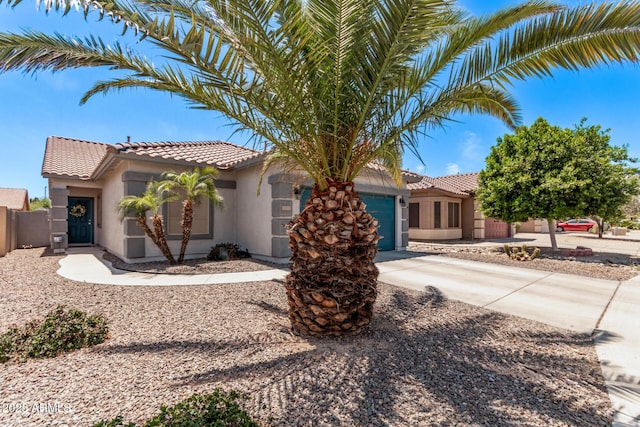 view of front of house featuring a garage, a tiled roof, driveway, and stucco siding