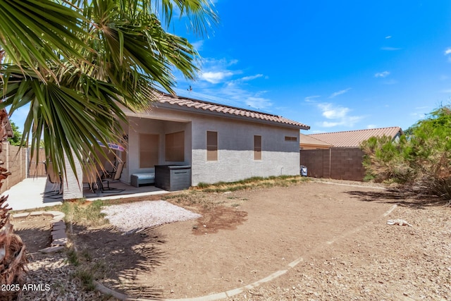 exterior space with stucco siding, a fenced backyard, solar panels, a patio, and a tiled roof