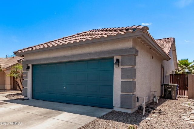 exterior space with stucco siding, an attached garage, driveway, and a tile roof
