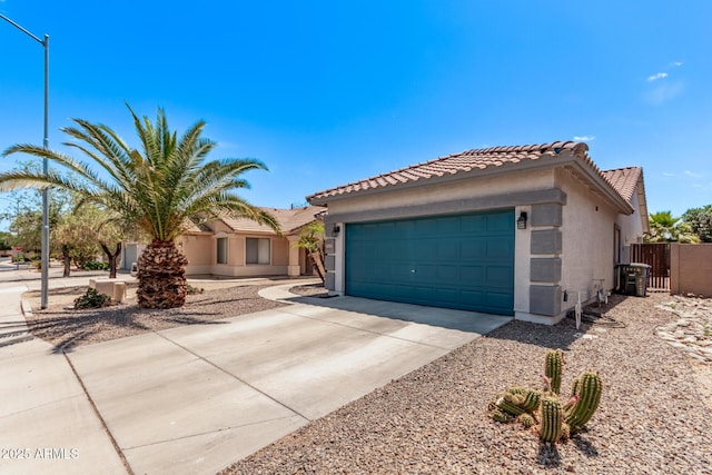 mediterranean / spanish-style home with a tile roof, a garage, fence, concrete driveway, and stucco siding