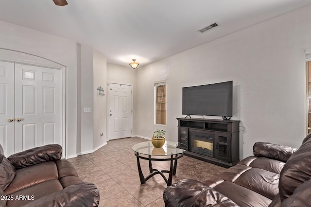 tiled living room featuring visible vents, baseboards, and a glass covered fireplace