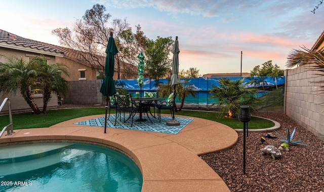 pool at dusk with a patio area and a fenced backyard