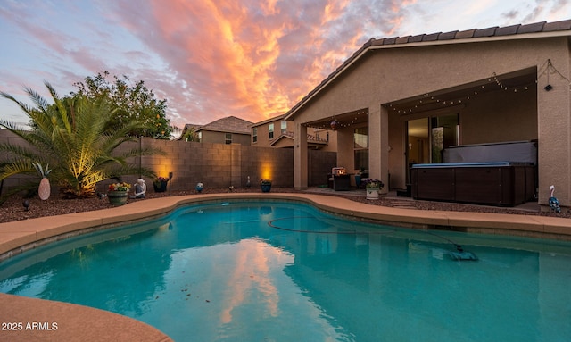 pool at dusk with a patio area, a hot tub, a fenced in pool, and a fenced backyard