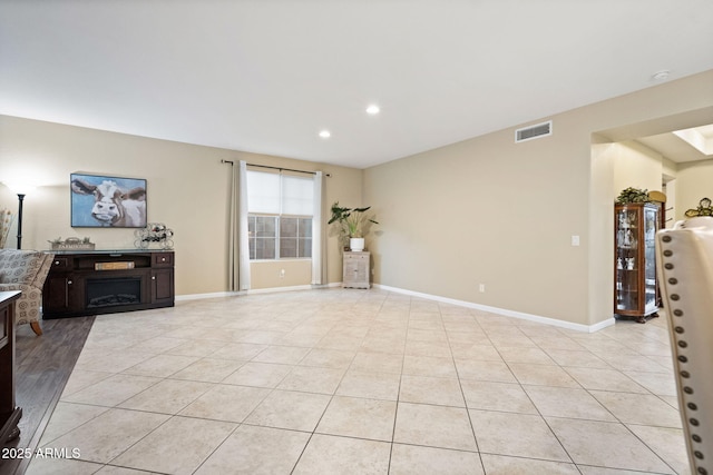 living room featuring light tile patterned floors, baseboards, a fireplace, and visible vents