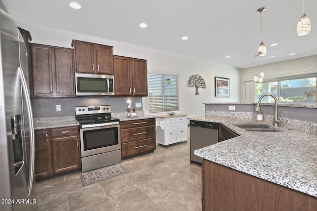 kitchen featuring dark brown cabinetry, hanging light fixtures, stainless steel appliances, and sink