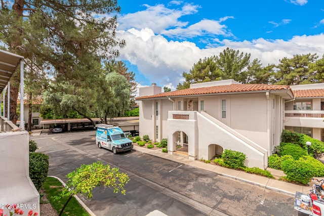 5200 S Lakeshore Dr Unit 206, Tempe, AZ 85283 - view of property exterior featuring covered and uncovered parking, a chimney, a tiled roof, and stucco siding