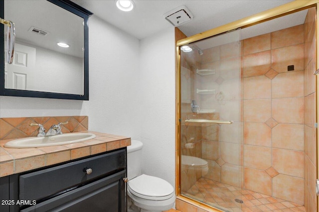 bathroom with vanity, toilet, and a shower with shower door