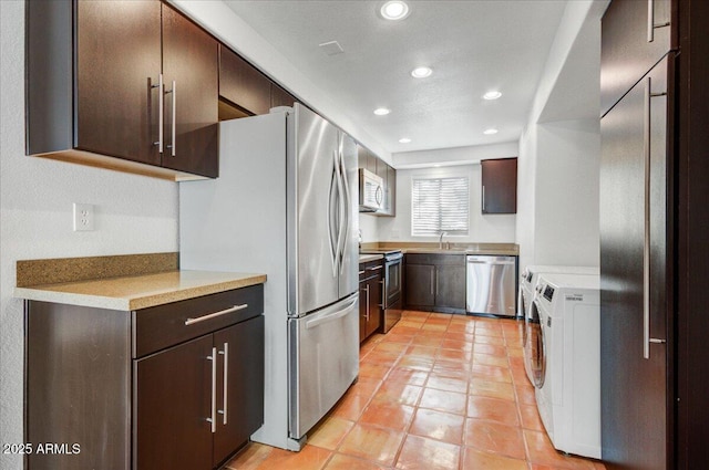 kitchen with sink, independent washer and dryer, stainless steel appliances, light tile patterned flooring, and dark brown cabinetry