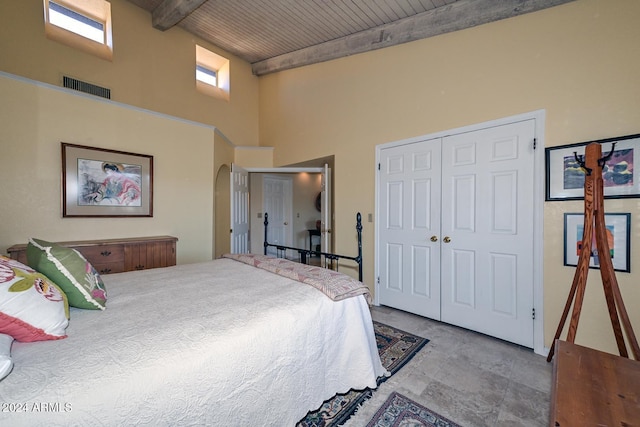 bedroom featuring a towering ceiling, beamed ceiling, wood ceiling, and a closet