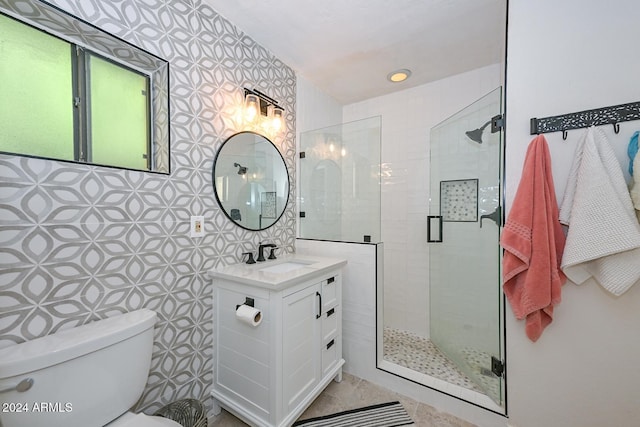 bathroom featuring vanity, toilet, tile walls, and a shower with shower door