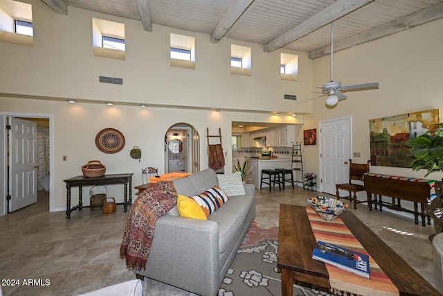 living room featuring a towering ceiling, wood ceiling, beamed ceiling, and ceiling fan