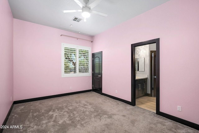 unfurnished bedroom featuring ceiling fan, light carpet, and ensuite bathroom